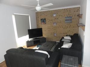 阿德莱德优越位置宽敞度假屋的客厅配有2张黑色沙发和平面电视。
