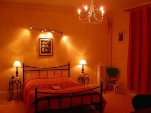 Moulins-la-Marche海豚酒店的一间卧室配有一张床、两盏灯和吊灯。