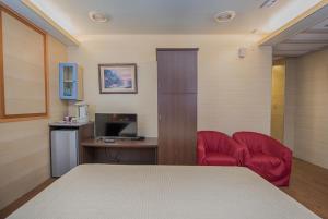 台北东皇渡假旅店的客房设有一张床和一张带红色椅子的书桌