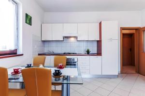扎达尔安德烈公寓的厨房配有白色橱柜和桌椅