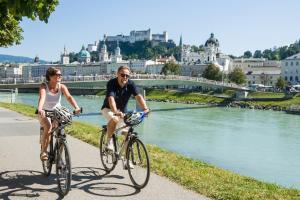 萨尔茨堡附近奥伯恩多夫奥特奥本多夫酒店的骑着自行车的男人和女人在河边