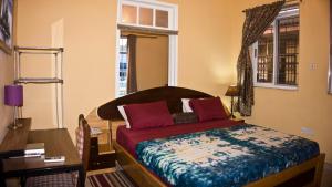 阿克拉Jesiwa B's Little Palace的一间卧室配有一张床、一张书桌和一个窗户。