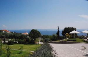 Khrónia星盘酒店的享有带遮阳伞的花园和大海的景致。