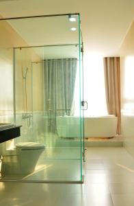 广义坎坦酒店的一间带玻璃淋浴、卫生间和浴缸的浴室