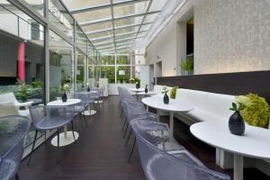 巴黎贝西广场酒店的餐厅设有白色的桌椅和窗户。