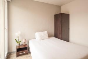 谢勒谢勒城市公寓酒店的卧室配有白色的床和木制橱柜。