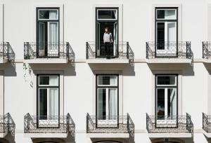 里斯本The Lisboans Apartments的站在建筑的阳台上的人