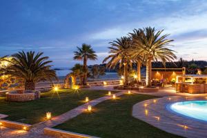 阿里克海滩费尼卡斯酒店 的一个带游泳池、棕榈树和灯的度假村