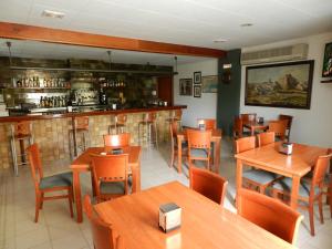 卡拉费尔Hotel El Castell的一间带木桌椅的餐厅和一间酒吧