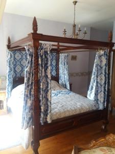 Sainte-Croix-Grand-TonneChateau des Chevaliers de Grand Tonne的一间卧室配有天蓬床和蓝白色窗帘