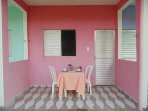 Armação do TairuPousada Praia de Tairu的粉红色墙壁的房间里一张桌子和椅子