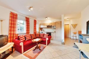 HildersLandhaus Will的一间带红色沙发的客厅和一间厨房