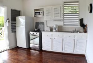 马里戈特湾Oasis Marigot的厨房配有白色橱柜和白色冰箱。