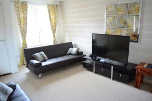 格拉斯哥Glasgow Hampden House的客厅配有黑色沙发和平面电视。