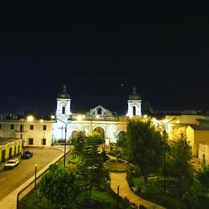 阿雷基帕Hotel Plaza San Antonio Arequipa的一座大型建筑,晚上有两座塔楼