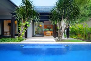 塞米亚克The Jineng Villas by Ekosistem的棕榈树屋前的游泳池