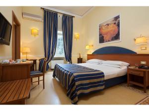 罗马肯尼迪酒店的酒店客房配有一张床、一张书桌和一台电视。