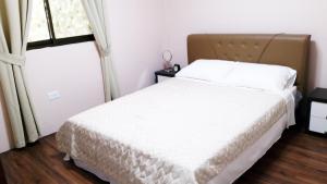 查兰卡诺亚塞班家庭公寓的卧室配有白色的床和窗户。