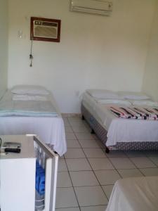 科曼达图巴岛Pousada São Nunca的一间设有两张床和一张桌子的房间