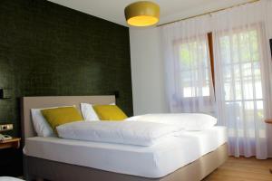 拉伊韦斯Gartenresidence Stephanie by Hotel Rotwand的一间卧室配有带白色床单和黄色枕头的床。