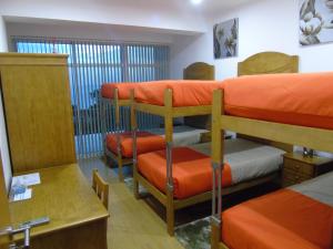 UrzelinaMarficas Hostel的带3张双层床和橙色床单的客房