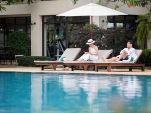 尖竹汶Maneechan Resort - SHA Extra Plus的三人坐在游泳池旁的躺椅上