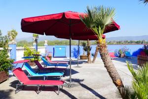 Banyeres del Penedes埃尔博斯克餐厅酒店的一组椅子和一把伞,旁边是棕榈树