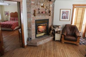 Petit-SaguenayB&B Les Deux Pignons的客厅设有砖砌壁炉和椅子