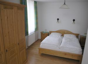 Pliening伏耳切汉墨兰德加斯托酒店的一间卧室配有一张带白色床单的床和橱柜。
