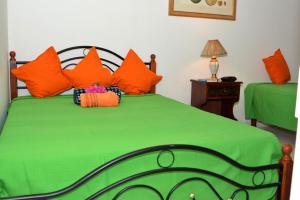 蒙特哥贝Paradise Palms Jamaica Vacation Rental的一间卧室配有带橙色枕头的绿色床
