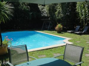 雷普隆吉斯Hostellerie Sarrasine - Mâcon Est的一个带两把椅子和遮阳伞的游泳池