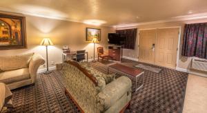 Reedley艾治沃特旅馆的一间配有沙发、一张桌子和一台电视的酒店客房