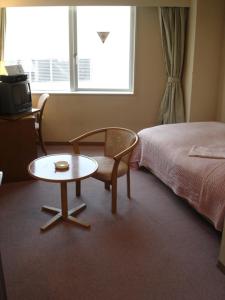 山形市新最上屋酒店的一间卧室配有桌子、床、桌子和椅子