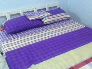 安吉利斯安吉利斯市旅馆的紫色的床,上面有紫色床单和枕头