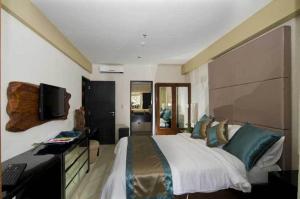 库塔库塔豪华酒店的一间卧室配有一张床、一张书桌和一台电视