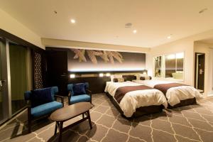 名户金秀喜瀬海滩宫殿酒店的一间卧室配有一张大床和两把椅子