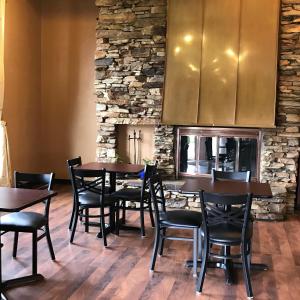 朗克斯Soudersburg Inn & Suites Lancaster的一间设有木桌和椅子的餐厅以及石墙