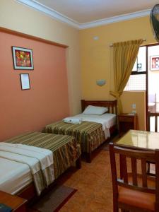 特鲁希略Hostal El Pillkay的酒店客房设有两张床和一张桌子。