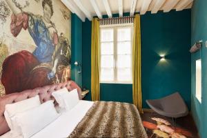 巴黎小磨坊酒店的卧室配有一张床,墙上挂有绘画作品