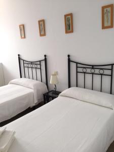 博罗尼亚Hostal Rios的卧室设有2张床和白色的墙壁。