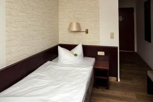 克滕安哈尔特酒店的一张位于带白色床单和桌子的房间的床铺
