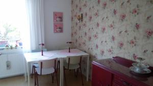 代尔夫特布鲁姆住宿加早餐旅馆的用餐室配有桌椅,墙上挂着鲜花