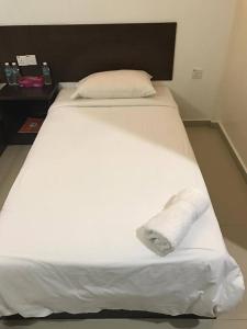 龙运里帕特湾海景宾馆的一张白色的床,上面有一条折叠毛巾