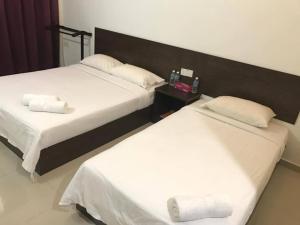龙运里帕特湾海景宾馆的配有白色床单的酒店客房内的两张床