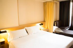 库马约尔居美奥克斯库马耶酒店的卧室配有一张白色大床和一把椅子