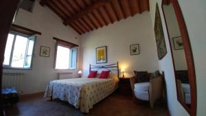 RoccalbegnaPodere Sant'Angelo的一间卧室配有一张带红色枕头的床和一把椅子