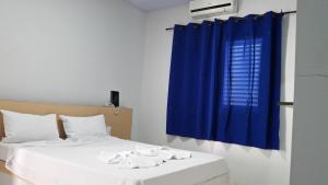 卡拉瓜塔图巴Hotel Cavalo Marinho Suítes的一间卧室配有两张床和蓝色窗帘