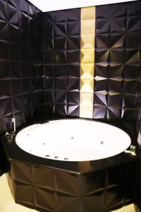 多列毛利诺斯阿诺斯50酒店的黑色瓷砖浴室设有白色浴缸