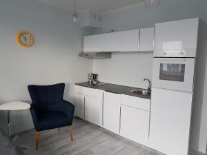 什切青Cukrownia的厨房配有白色橱柜、蓝色椅子和水槽