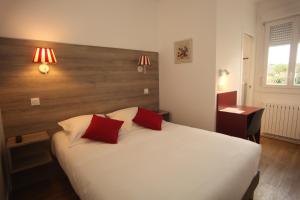 Ambazac旅行者之家酒店餐厅的卧室配有白色床和2个红色枕头